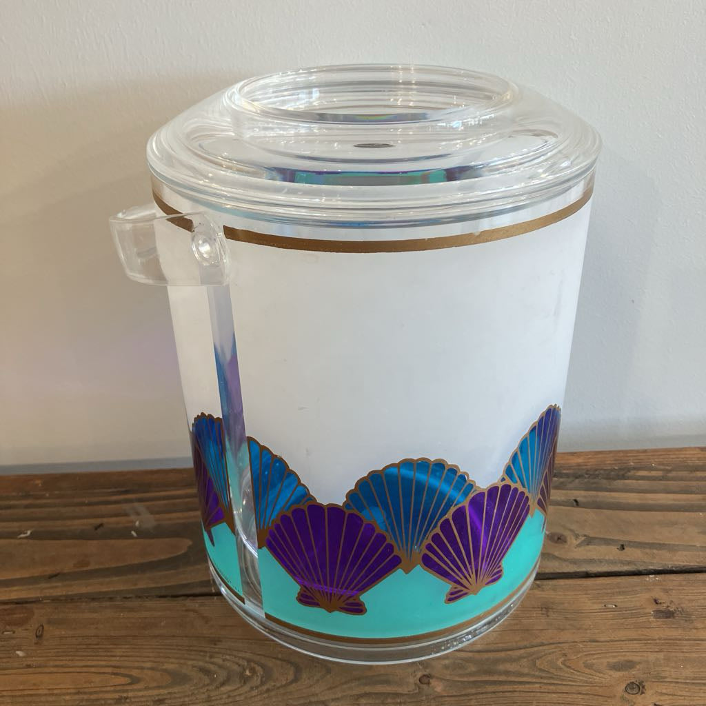 Clear plastic tumbler with purple and gold shell design on a wooden surface