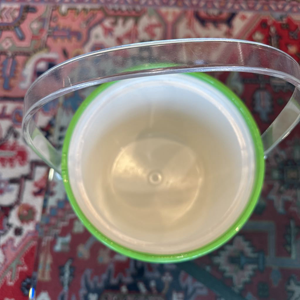Clear plastic container with a green lid on a patterned fabric background