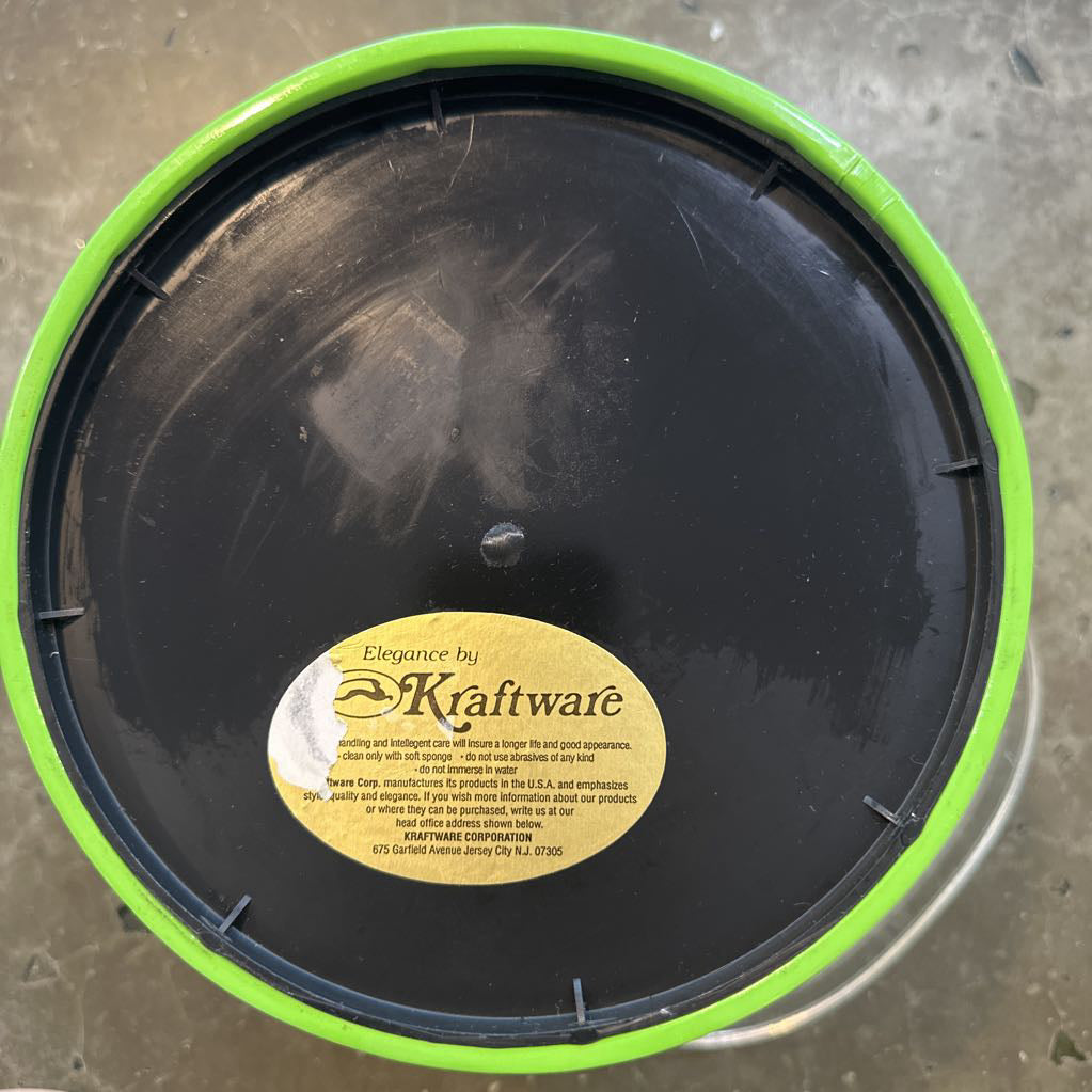 Black lid with a Kraftware label on a concrete surface