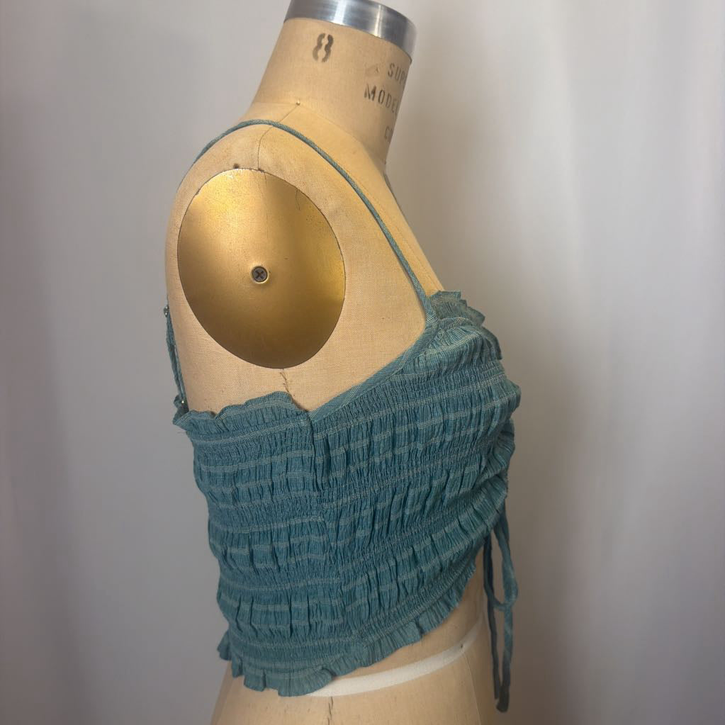 Teal crop top on a mannequin against a plain background