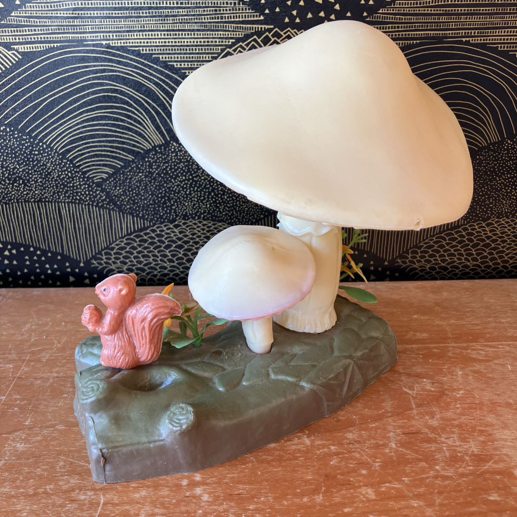 Decorative mushroom sculpture with a small figurine on a textured surface