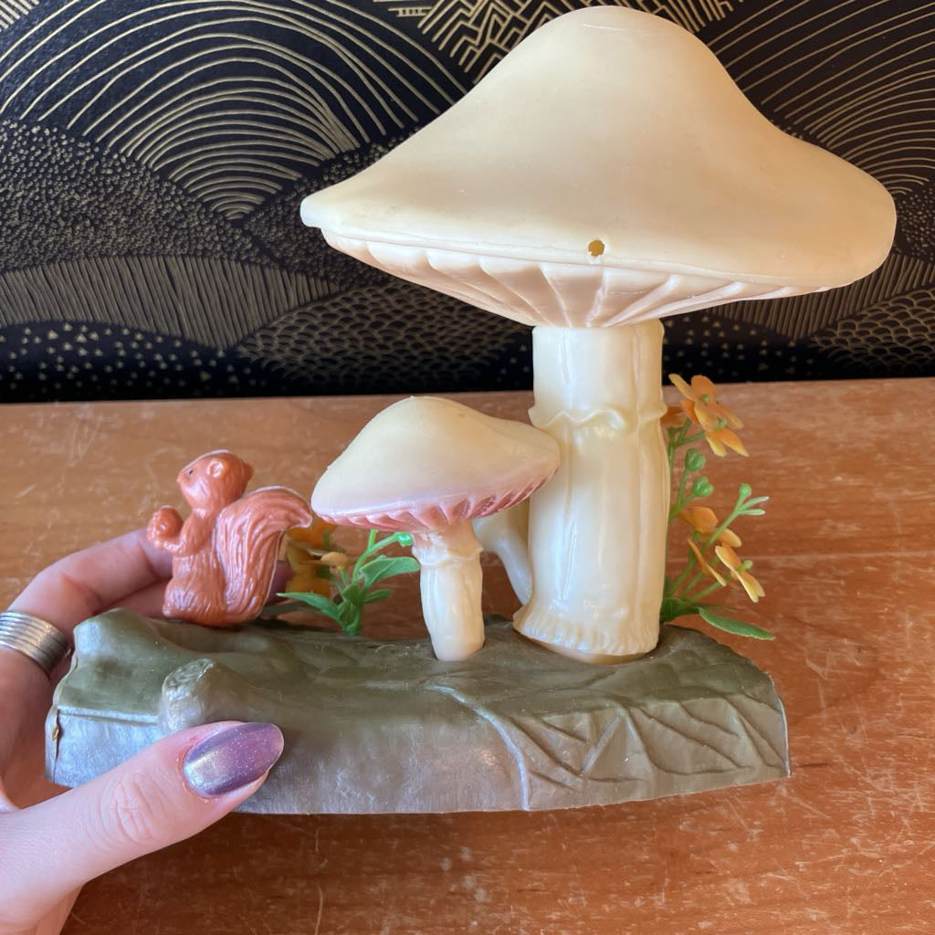 Decorative mushroom sculpture with a small figurine of a squirrel on a leaf-shaped base.