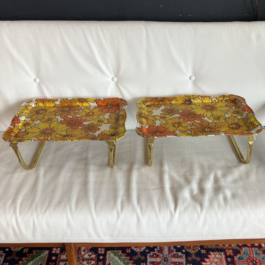 Two floral-patterned metal tables on a white surface.