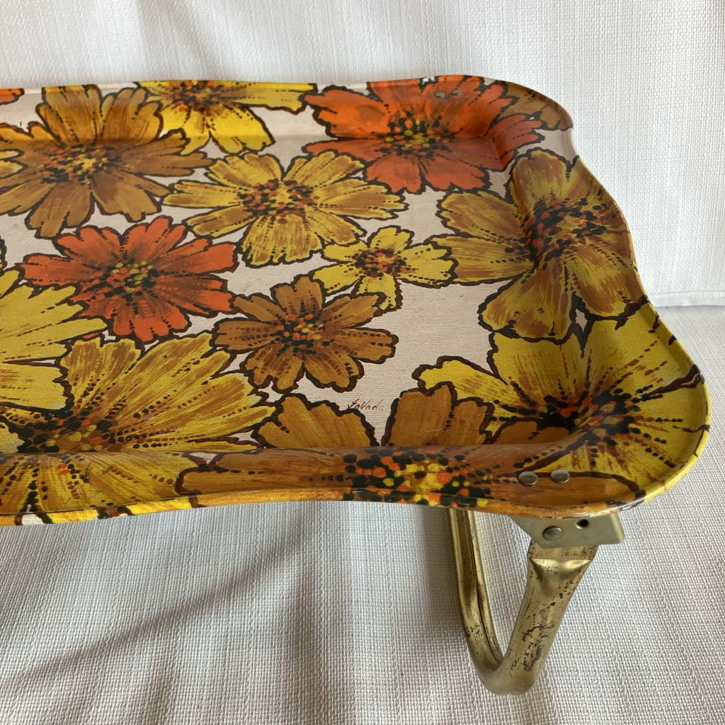 Floral-patterned tray with brass handle on a light background
