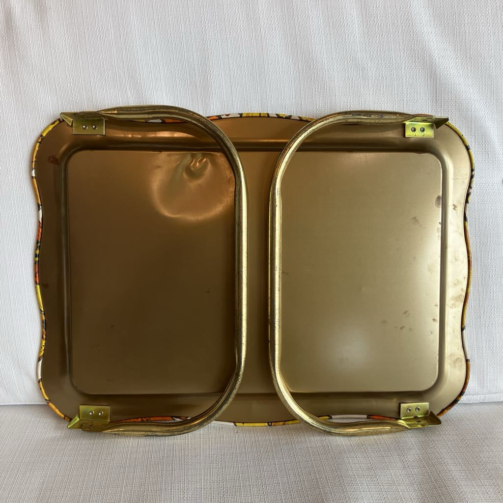 Two gold-colored metal trays with decorative edges on a white background