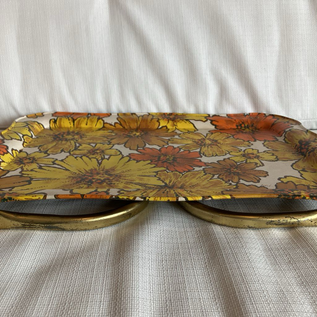 Floral-patterned tray with brass handles on a textured surface