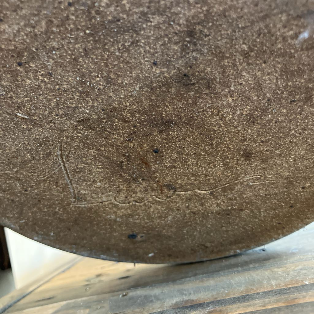A signature at the bottom of a ceramic pot.
