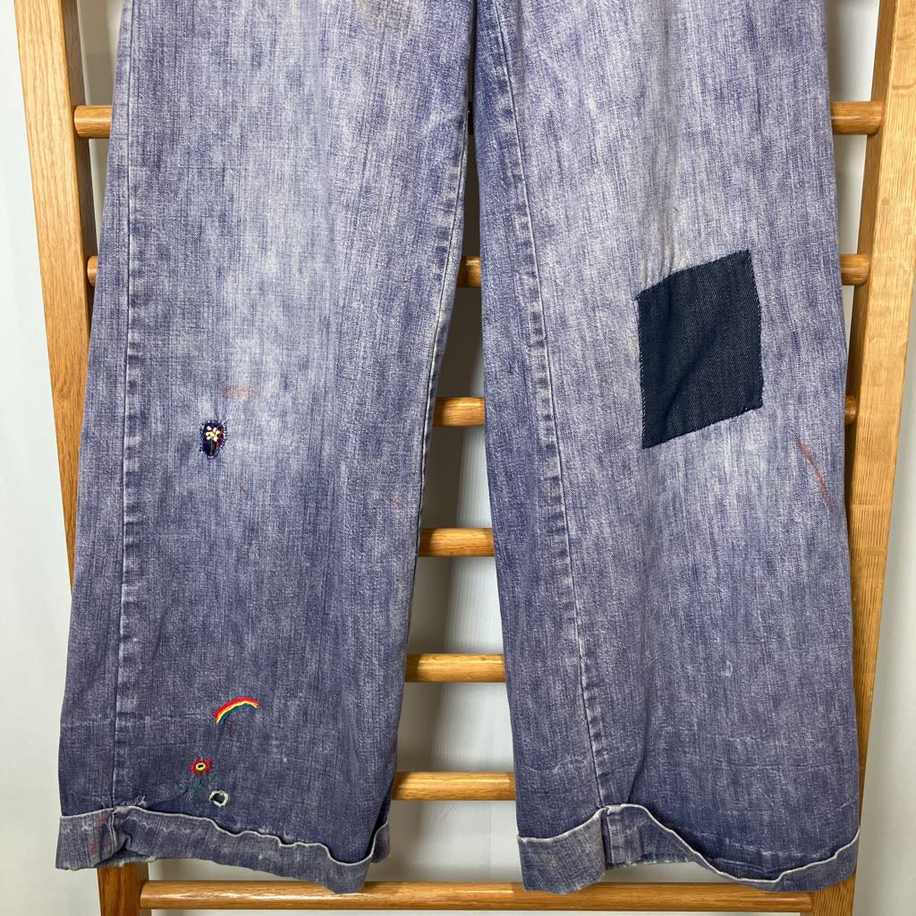 Blue denim jacket with patches and embroidery on a wooden rack