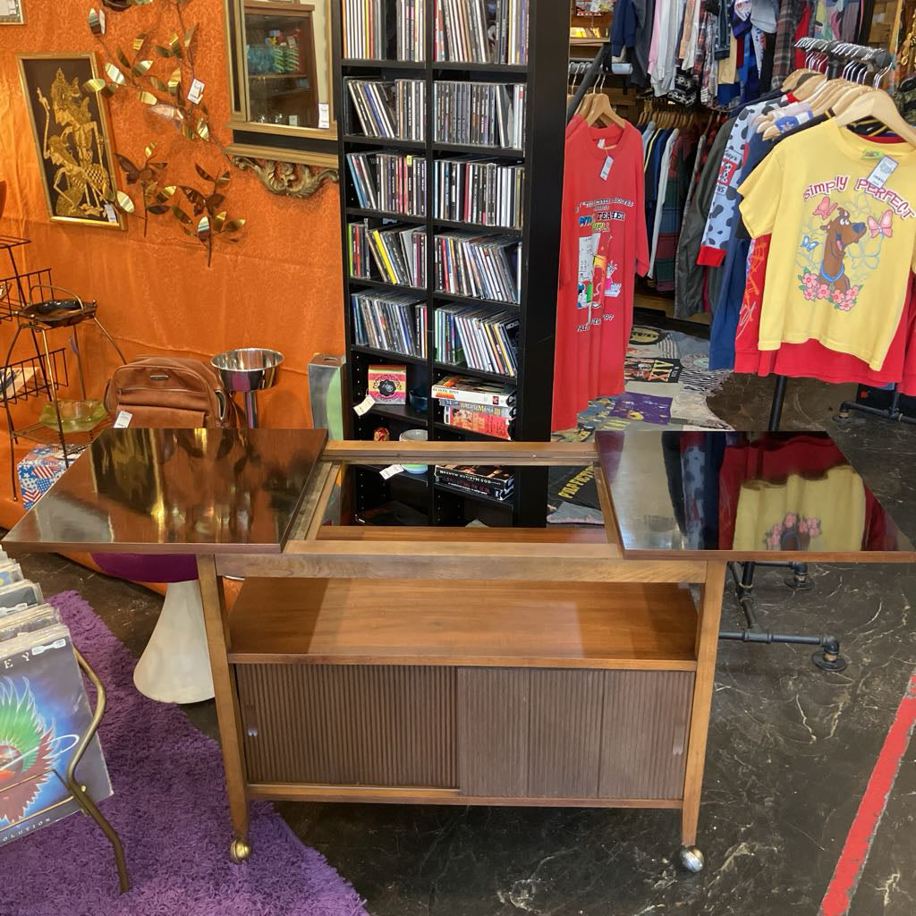 Vintage furniture store with wooden desk, books, and clothing items.