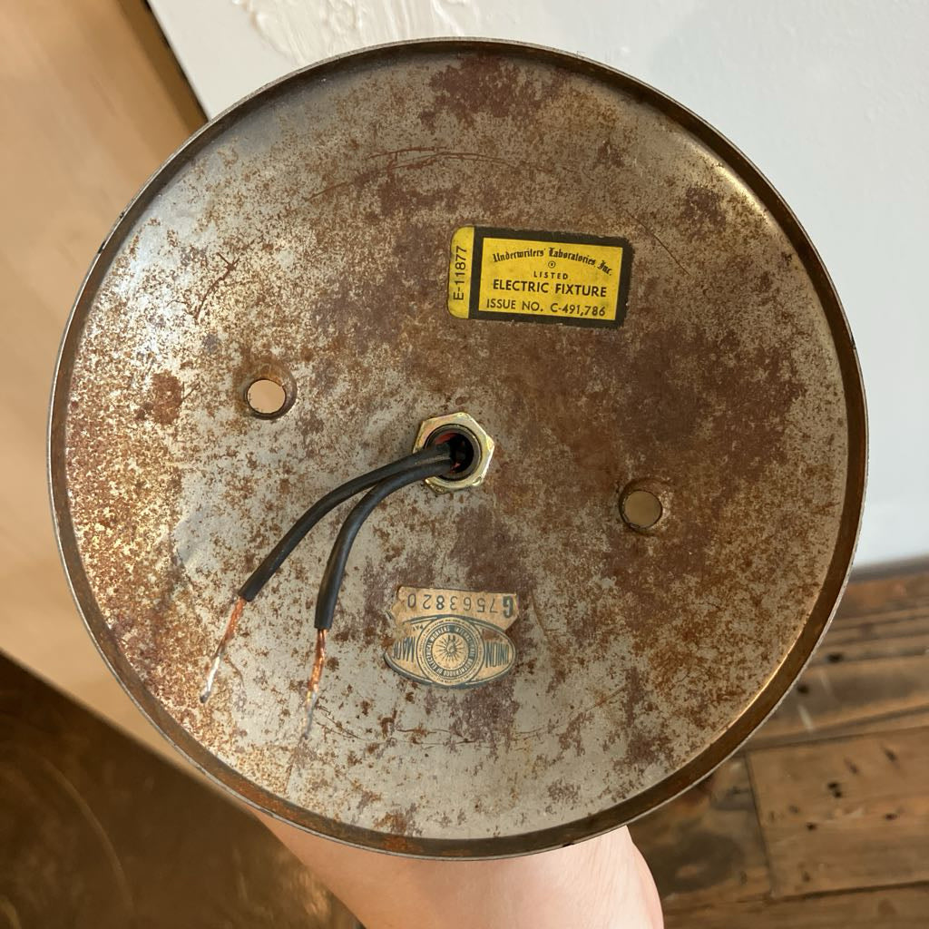 Rust-covered metal fixture with visible wiring, held by a hand.