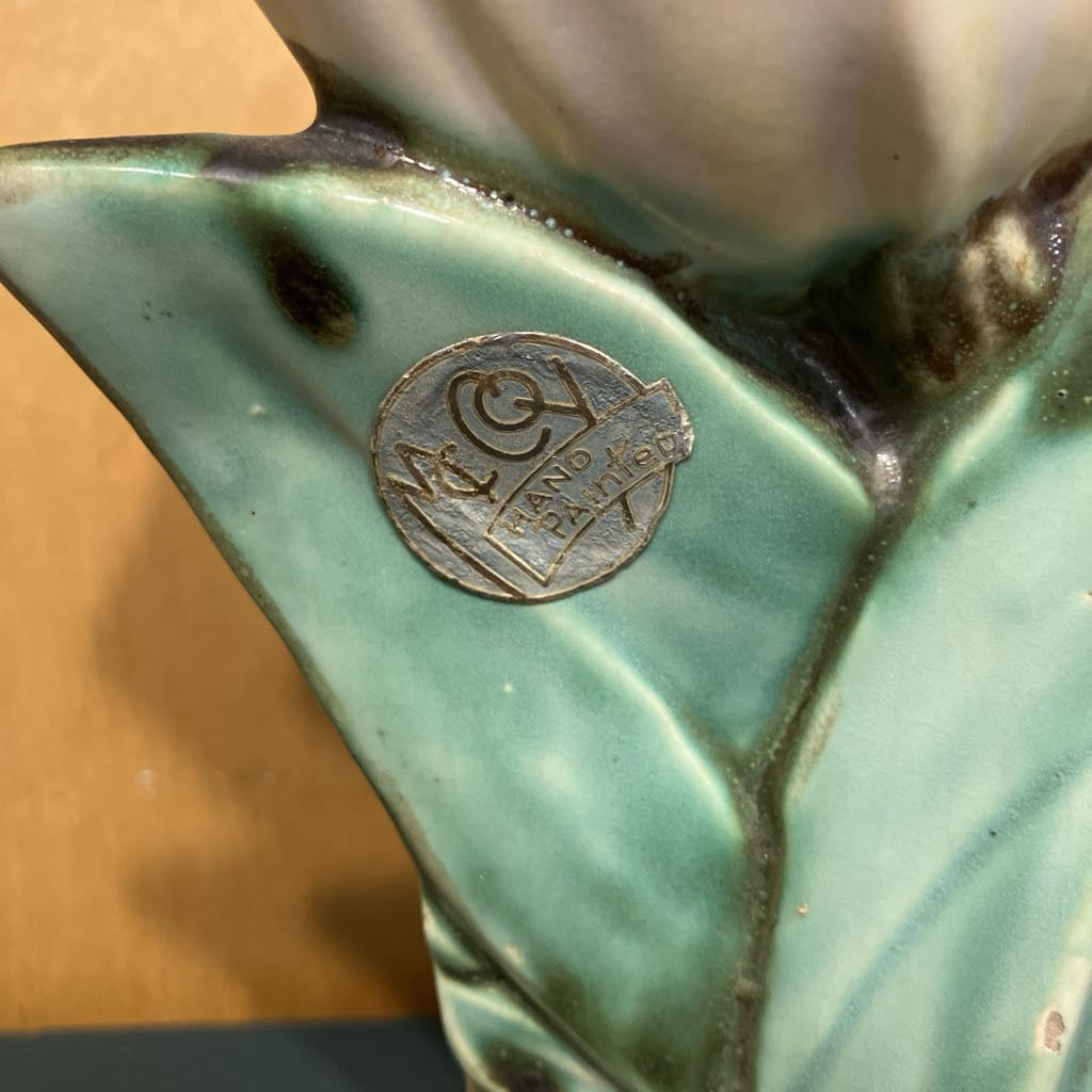 Close-up of a ceramic vase with a visible brand logo on a wooden surface