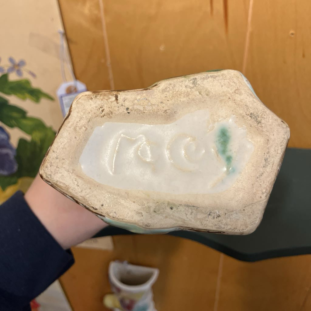 Hand holding a ceramic dish with a floral design on a wooden surface