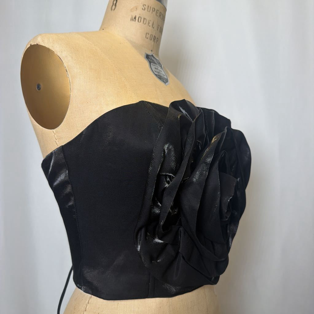 Photo of a black corset top with flower design on a mannequin against a white background