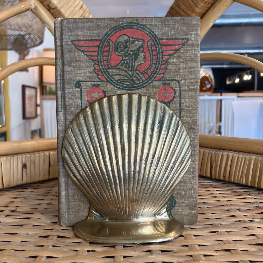 Brass shell-shaped object on a book with a vintage design