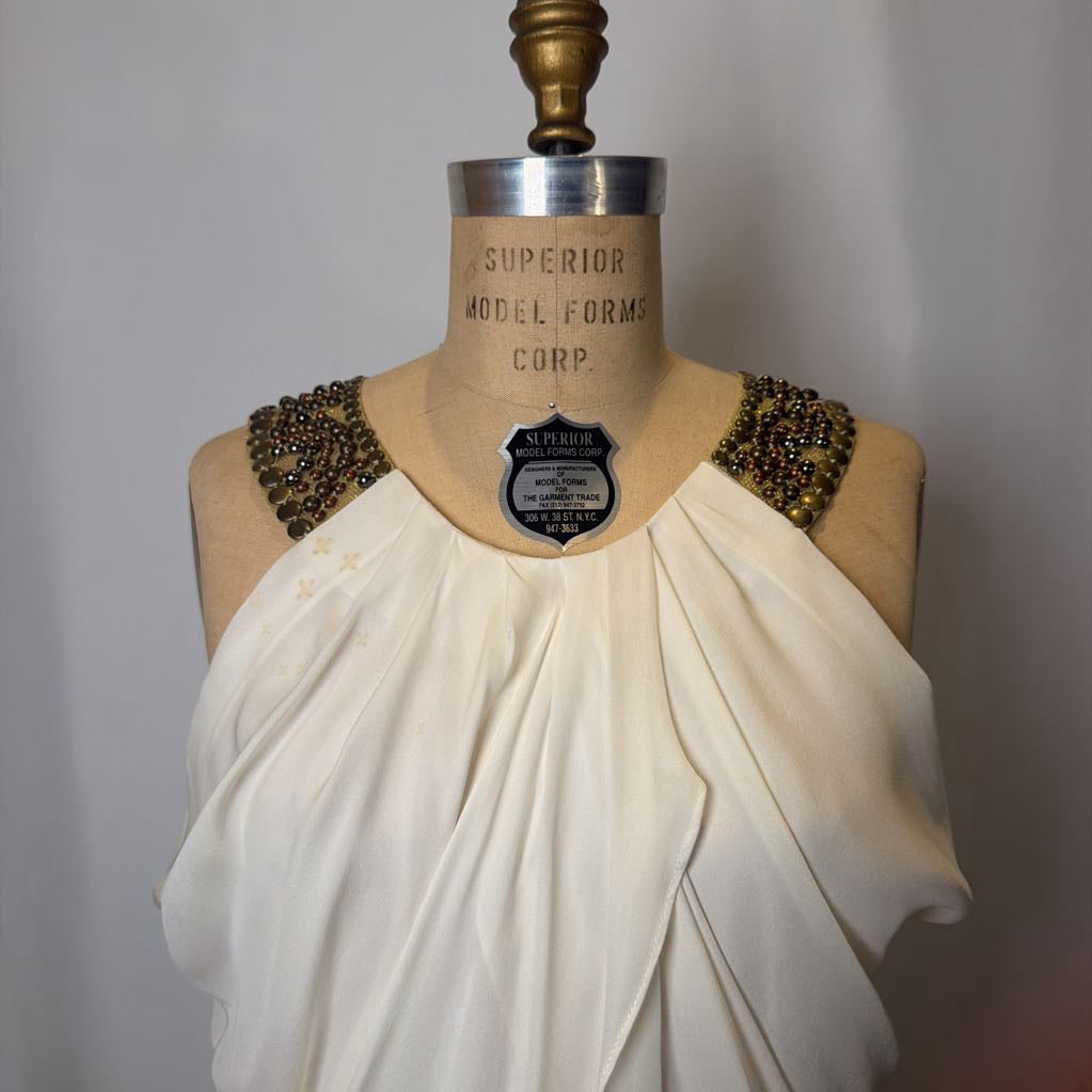 Mannequin wearing a white dress with embellished shoulders against a plain background
