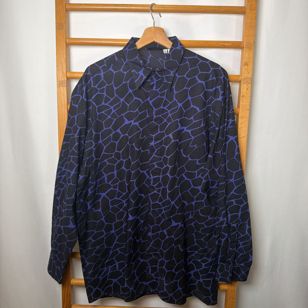 Blue patterned shirt on a wooden hanger against a white wall