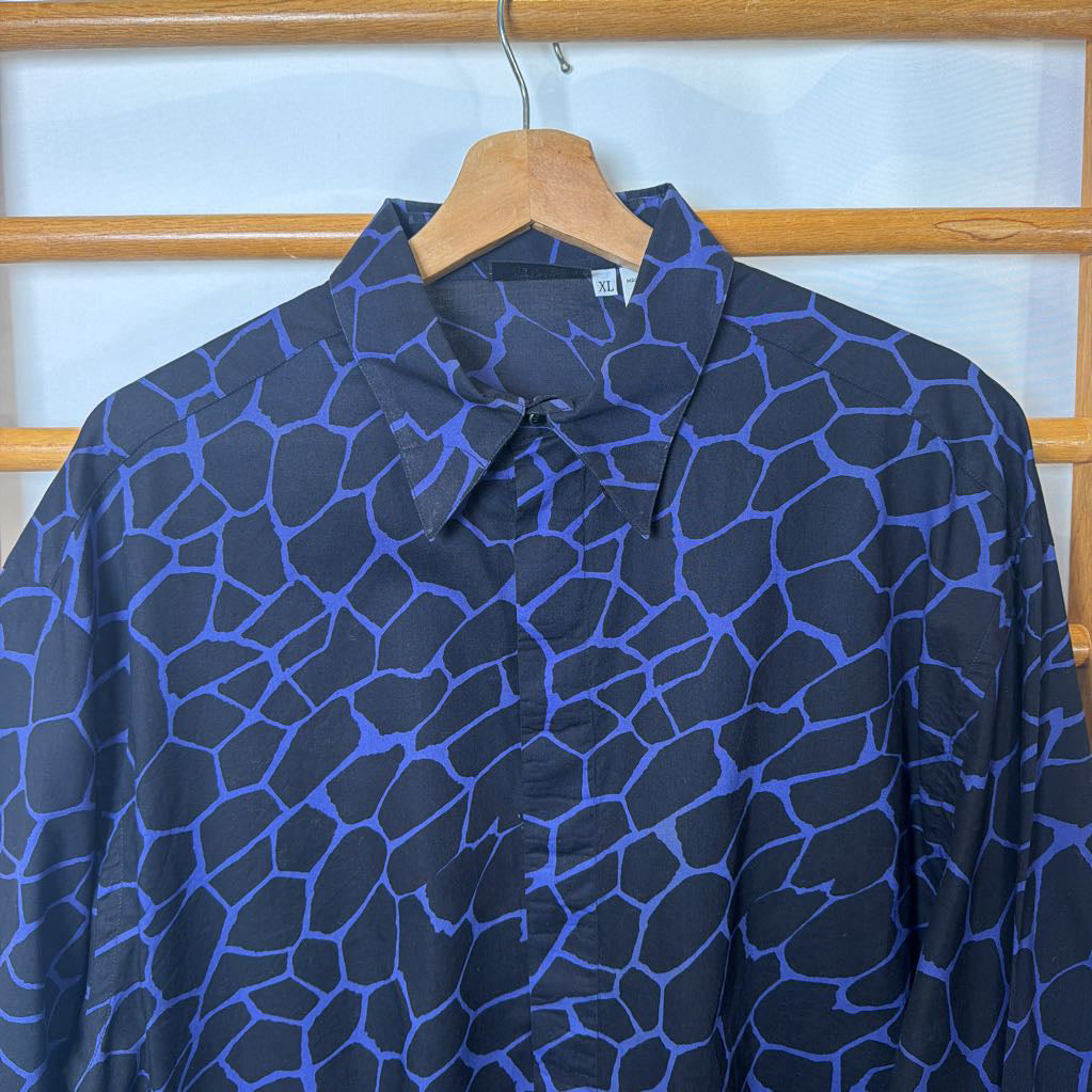 Blue patterned shirt on a hanger against a wooden lattice background