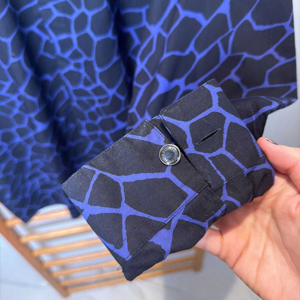 Black fabric with blue geometric pattern held by a hand against a blue textured background