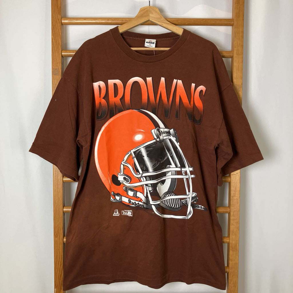 Brown t-shirt with Cleveland Browns logo on a wooden hanger against a white wall.