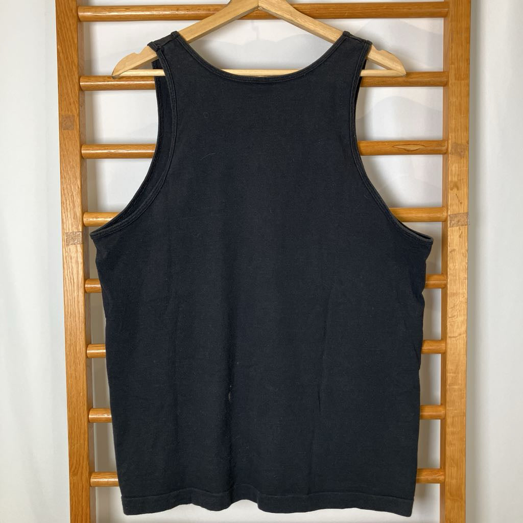 Black tank top hanging on a wooden rack against a white wall