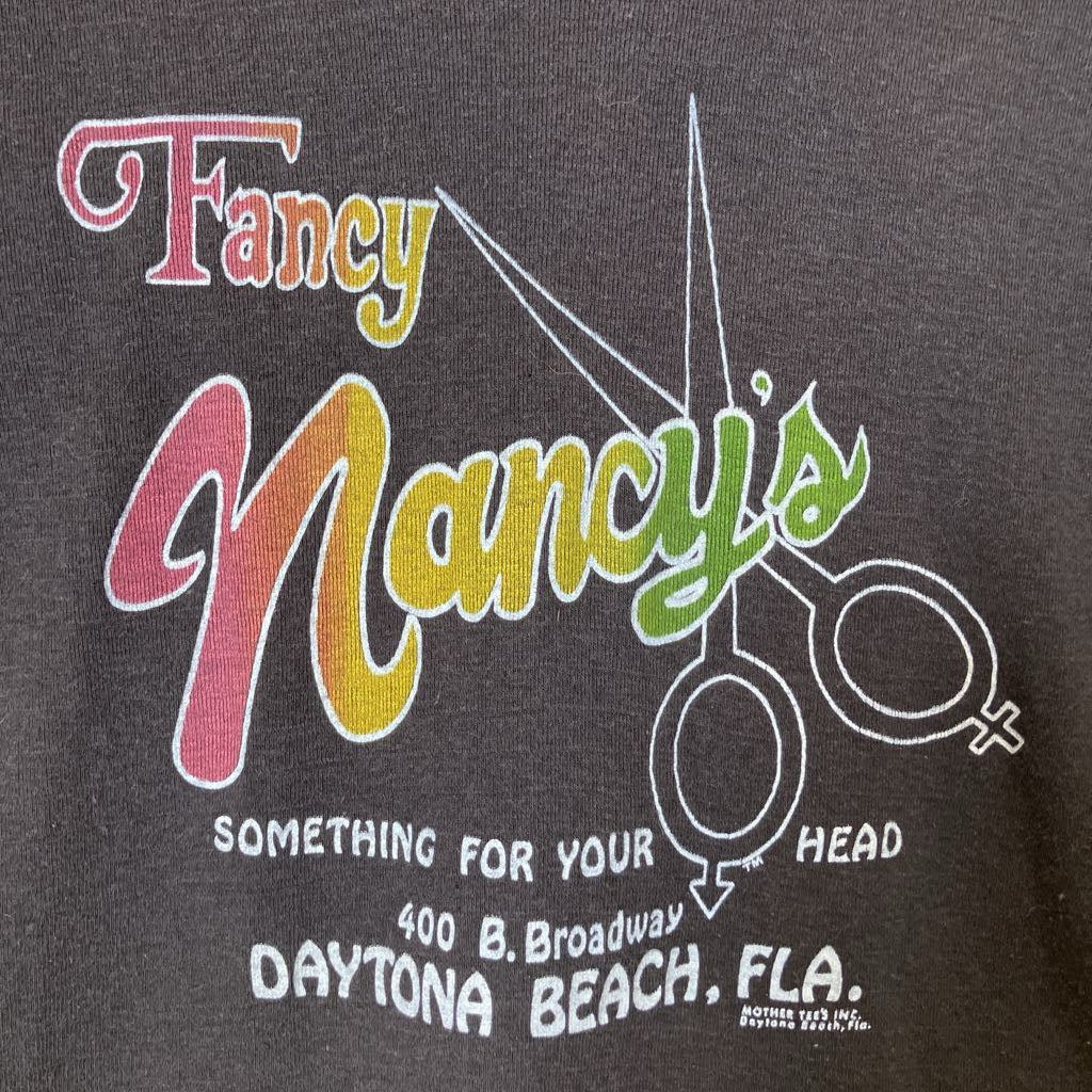 Logo of Fancy Nancy's with scissors and text on a dark background