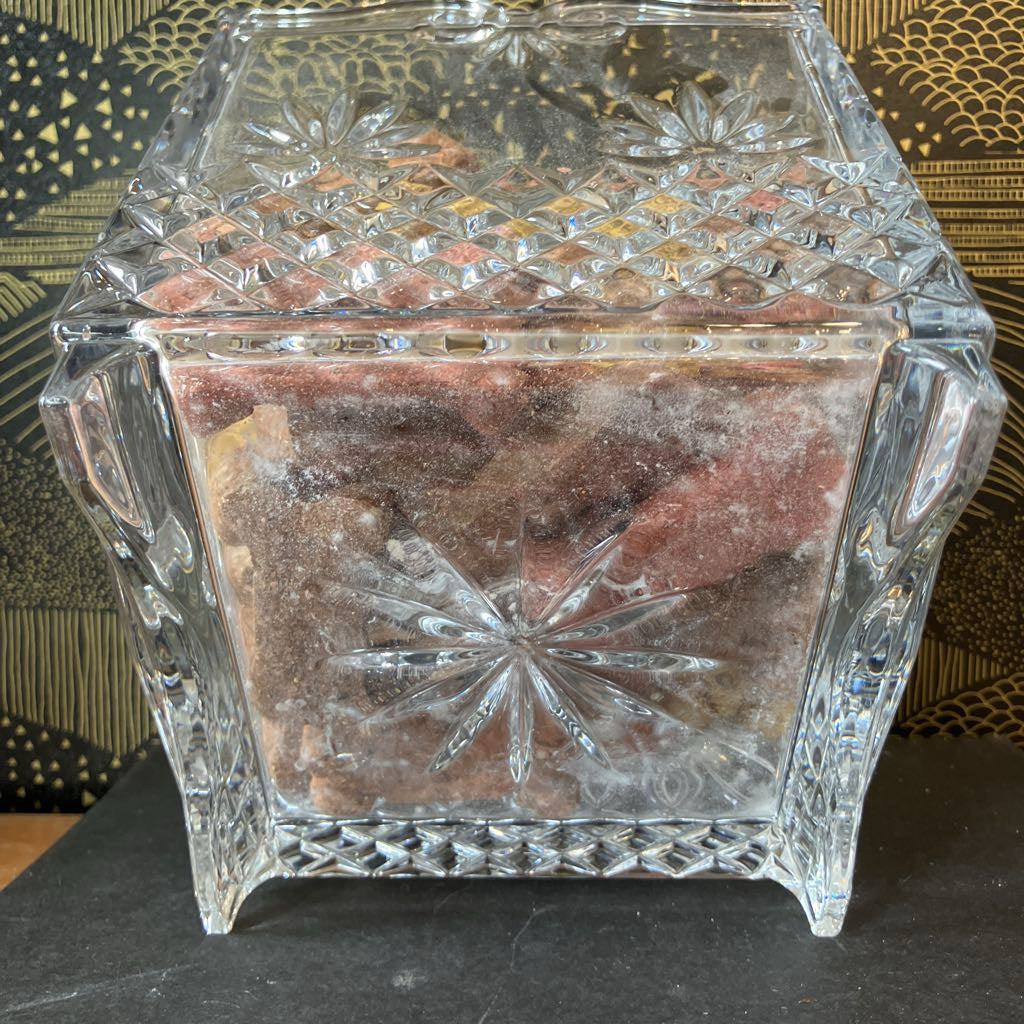 Decorative crystal box with intricate cut patterns on a dark surface.