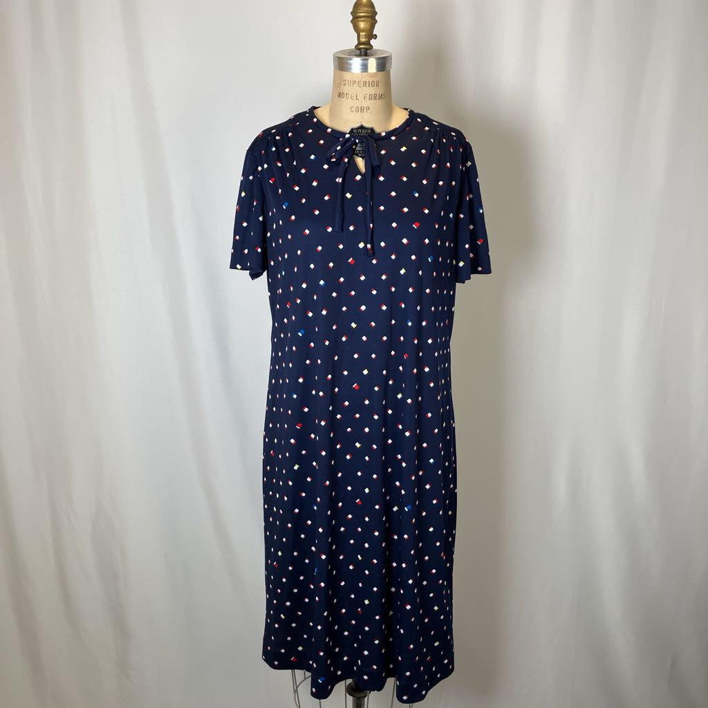 Navy dress with white and red polka dots on a mannequin against a plain background