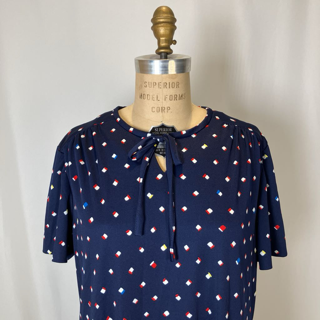 Navy blue blouse with colorful pattern on a mannequin against a plain background