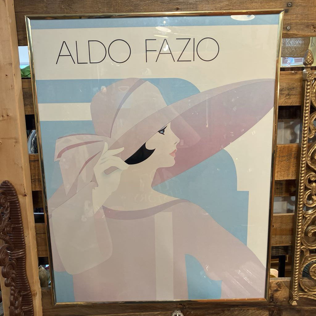 Framed poster of a woman with a large hat and 'Aldo Fazio' branding.