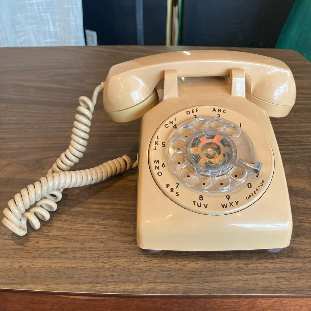 Beige rotary phone on a wooden surface