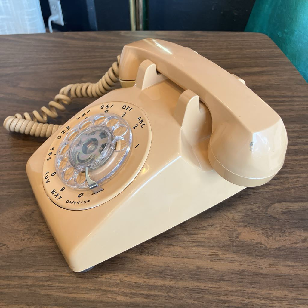 Beige rotary phone on a wooden surface