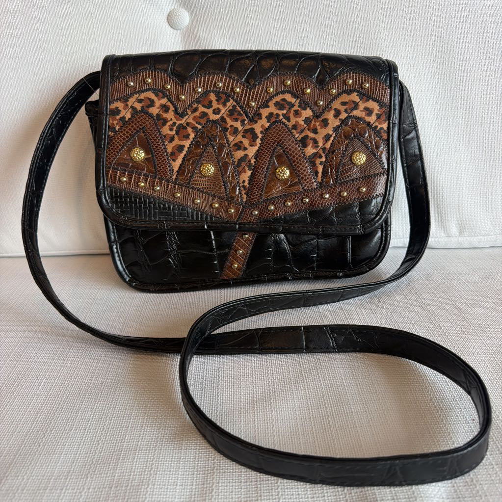 Leopard print handbag with black leather strap on a light surface