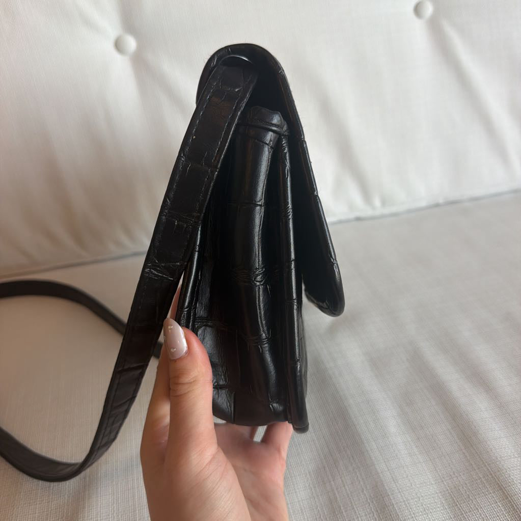 Black leather wallet held by a hand on a light background