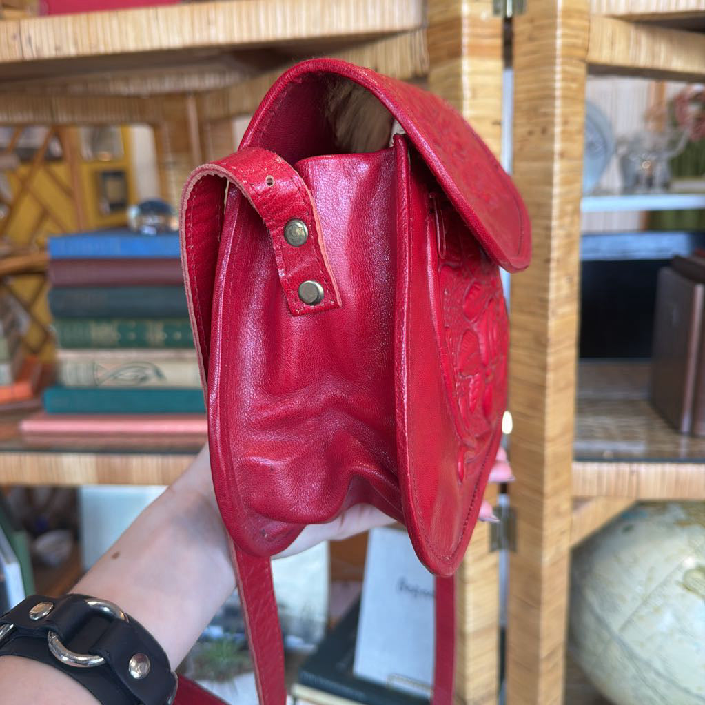 Red leather bag held by a person with a blurred background