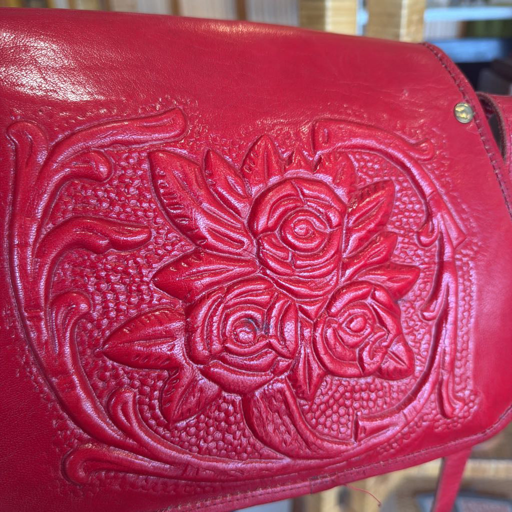 Red leather bag with floral embossing on a blurred background
