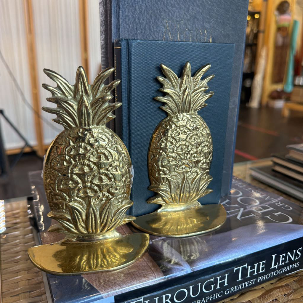 Showing 2 vintage mcm brass pineapple bookends on top of books.