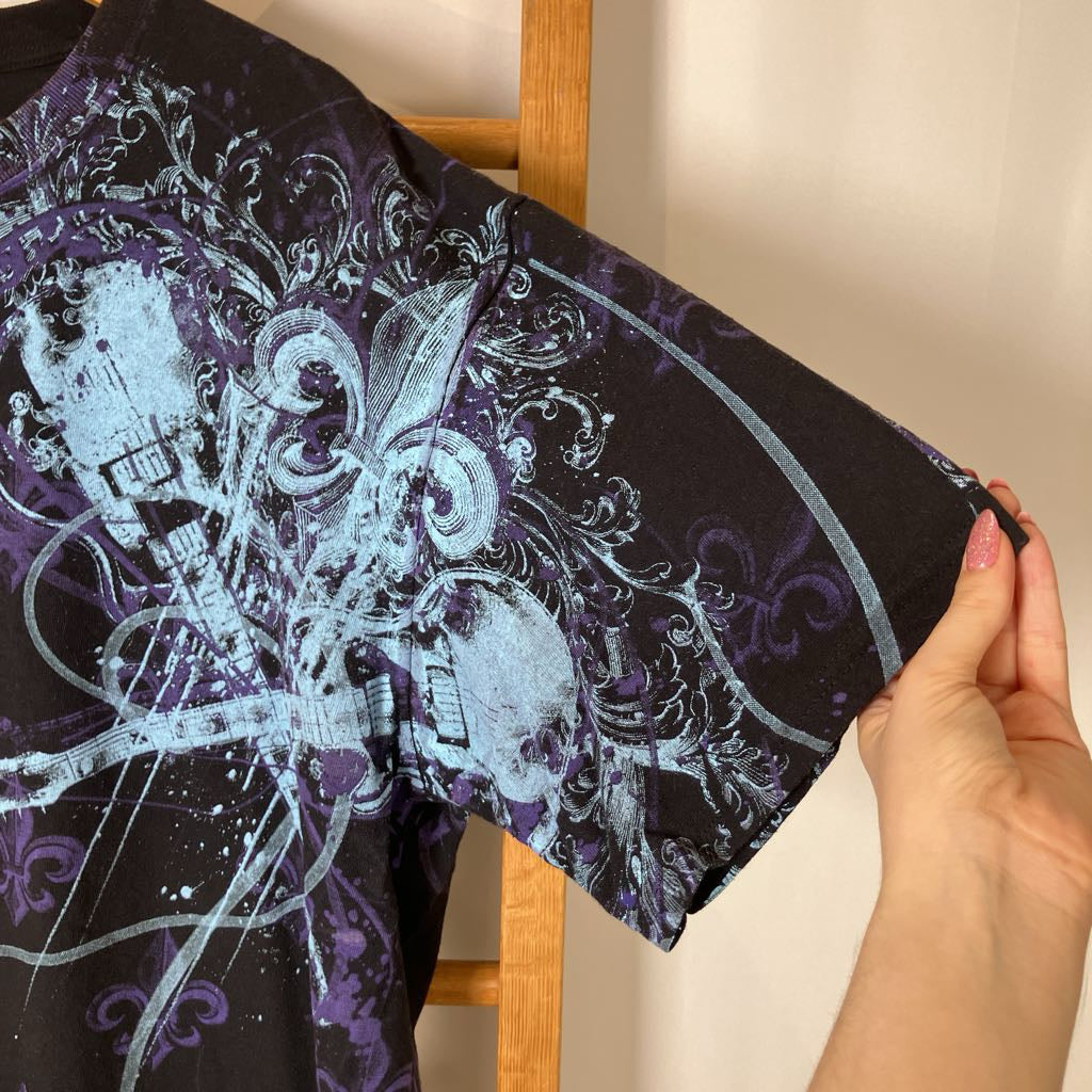 Black shirt with blue musical pattern held by a hand against a neutral background