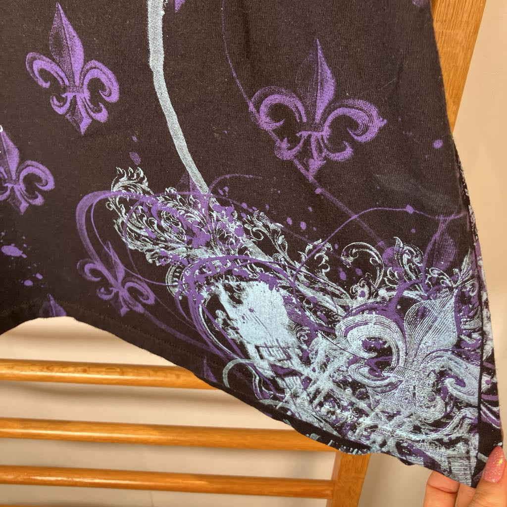 Black fabric with purple and white floral patterns held by a hand.