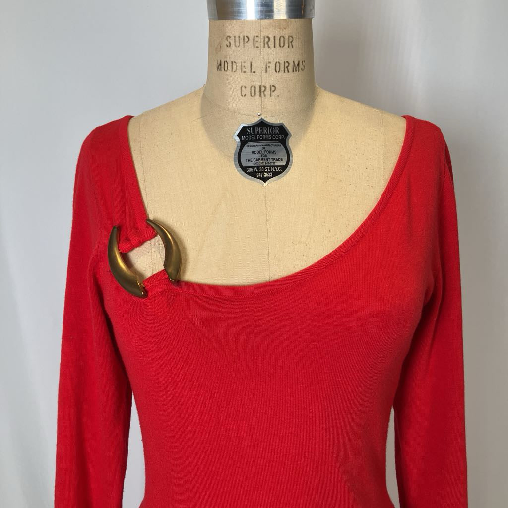 Red long-sleeve top with a gold accent on a mannequin against a plain background