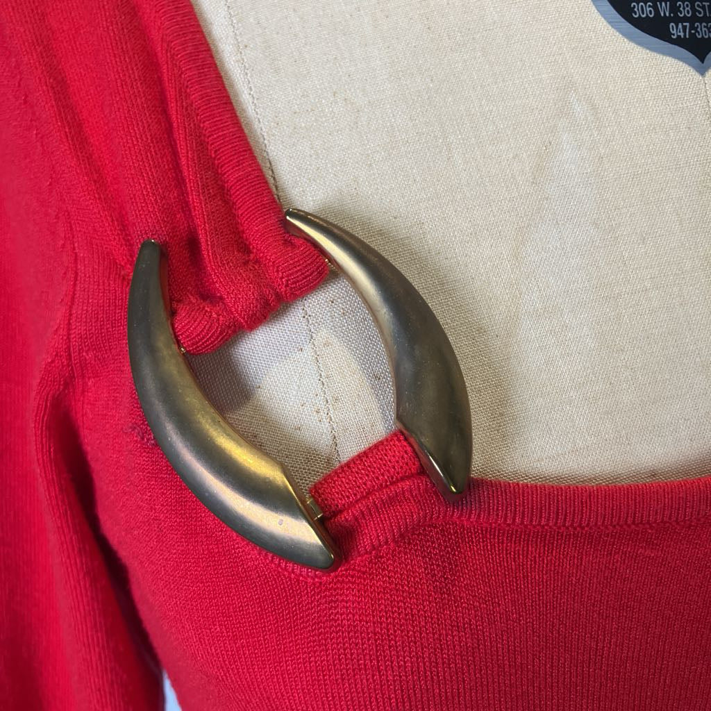 Close-up of a red garment with a metallic clasp on a beige background