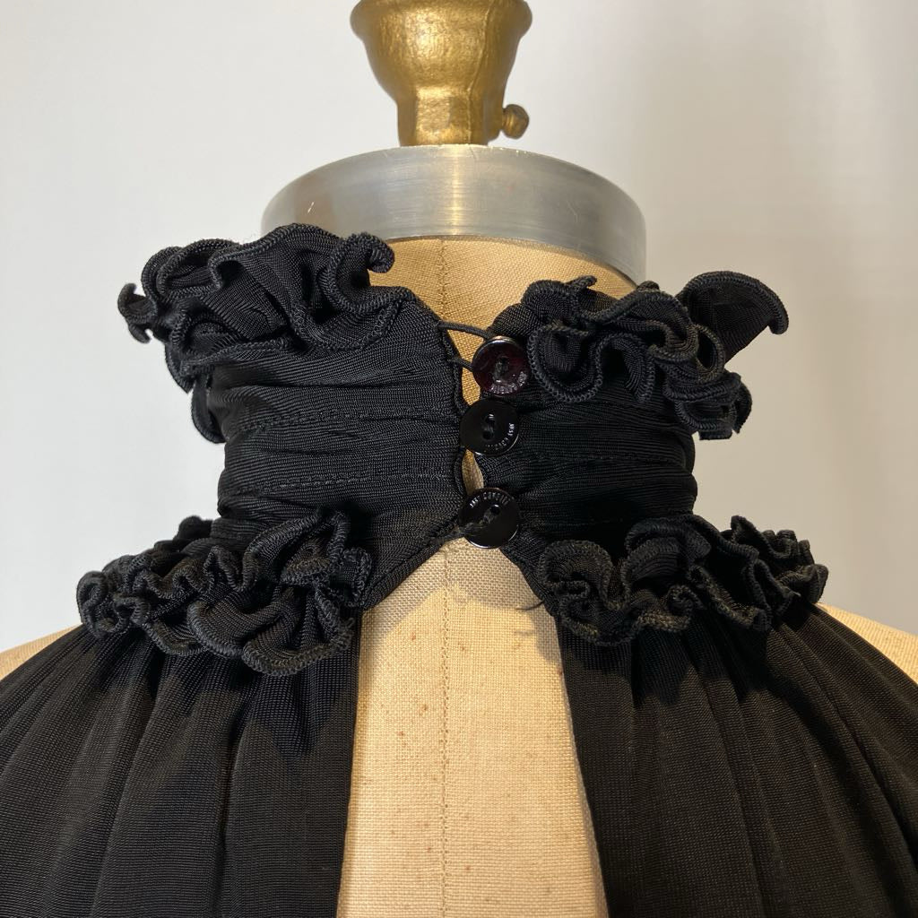 Black ruffled garment on a mannequin with a neutral background