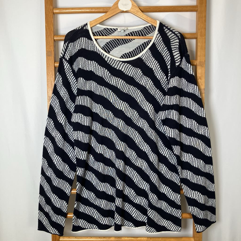 Black and white striped shirt on a wooden hanger against a white wall