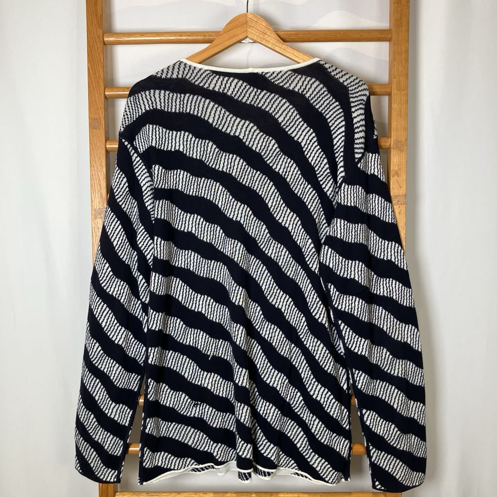 Black and white striped sweater on a wooden hanger against a white wall