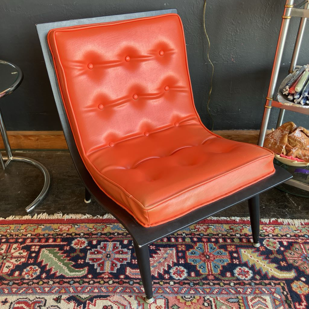 Orange mcm tufted vinyl scoop chair with walnut wood frame that has been painted black