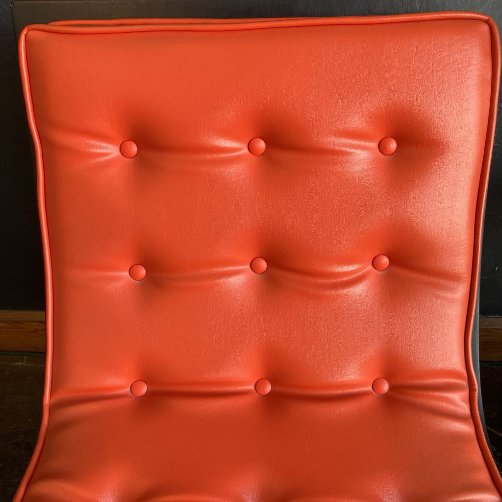 Orange mcm tufted vinyl scoop chair with walnut wood frame that has been painted black