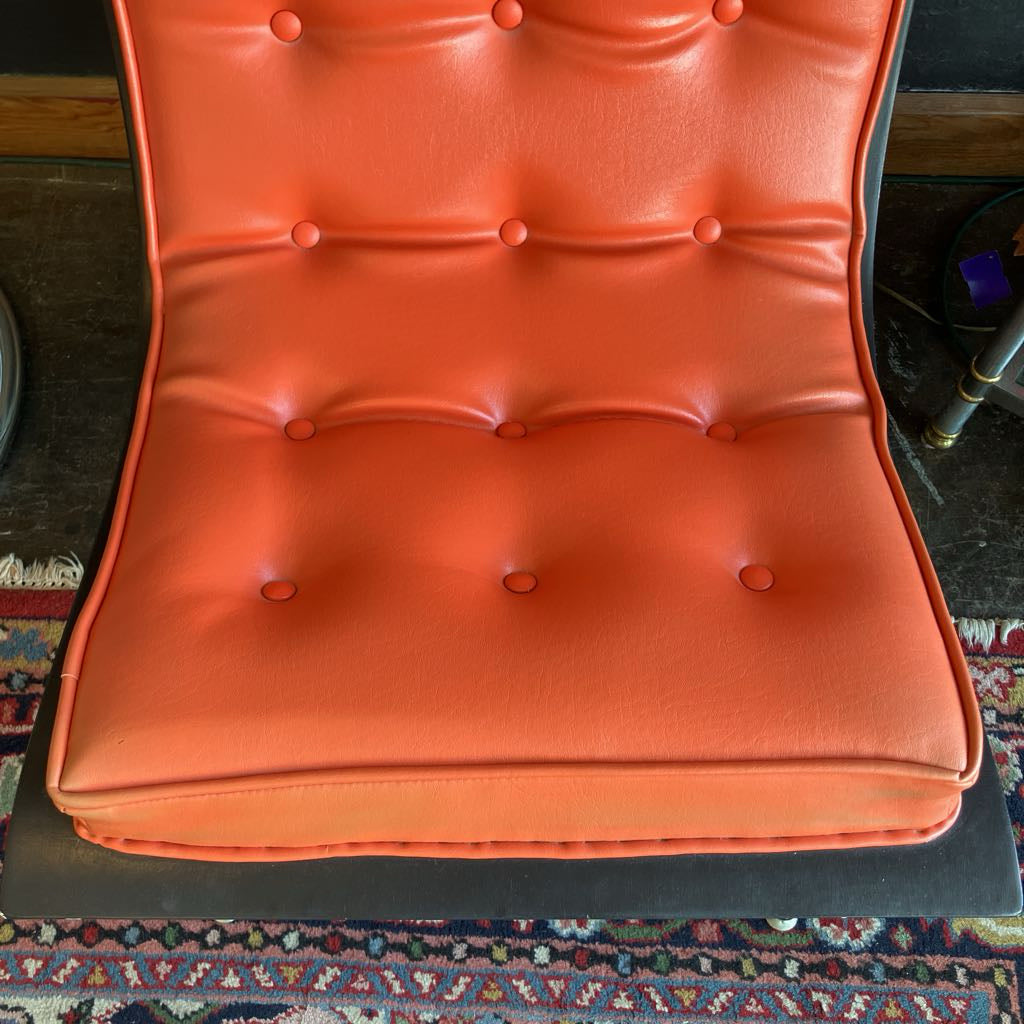 Orange mcm tufted vinyl scoop chair with walnut wood frame that has been painted black