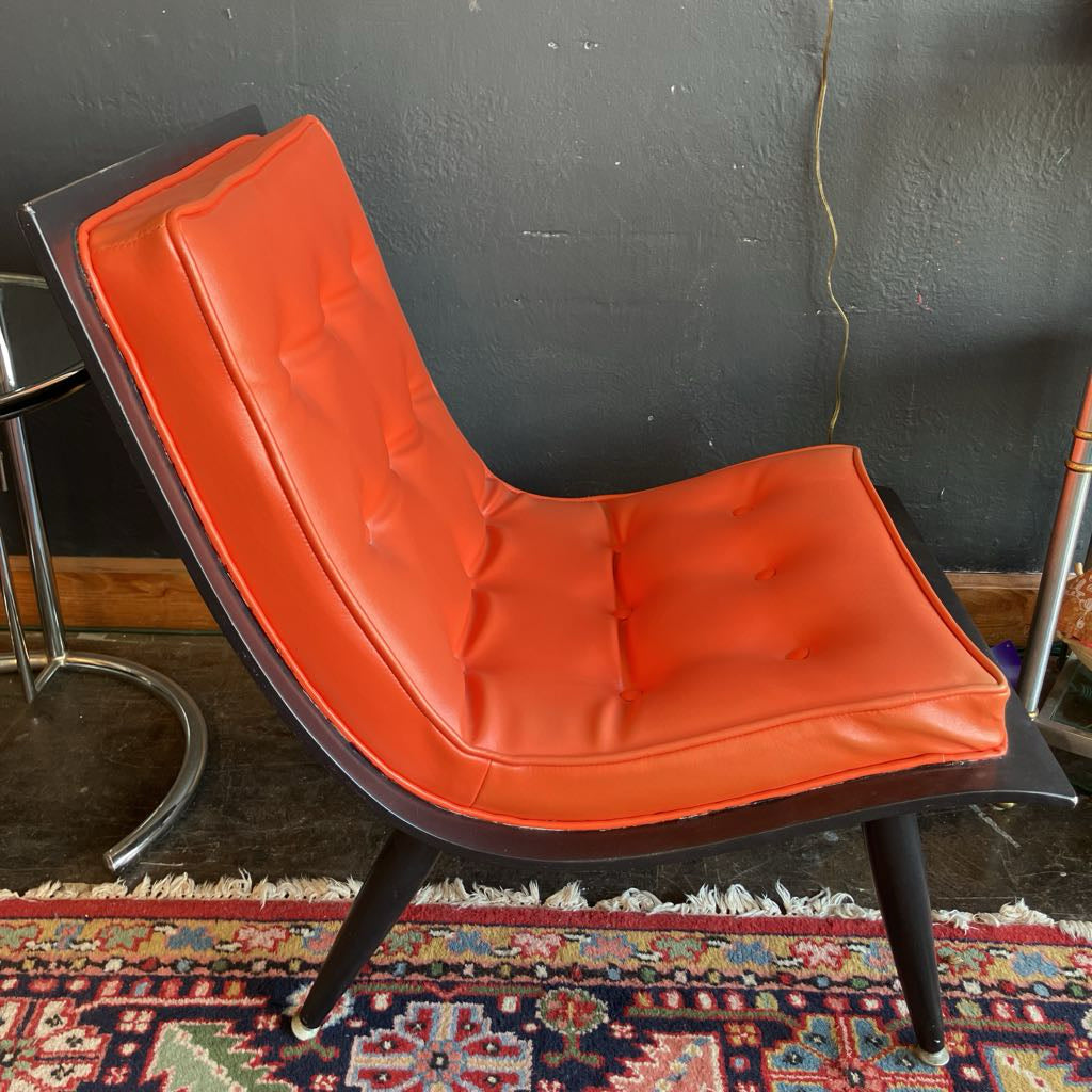 Orange mcm tufted vinyl scoop chair with walnut wood frame that has been painted black