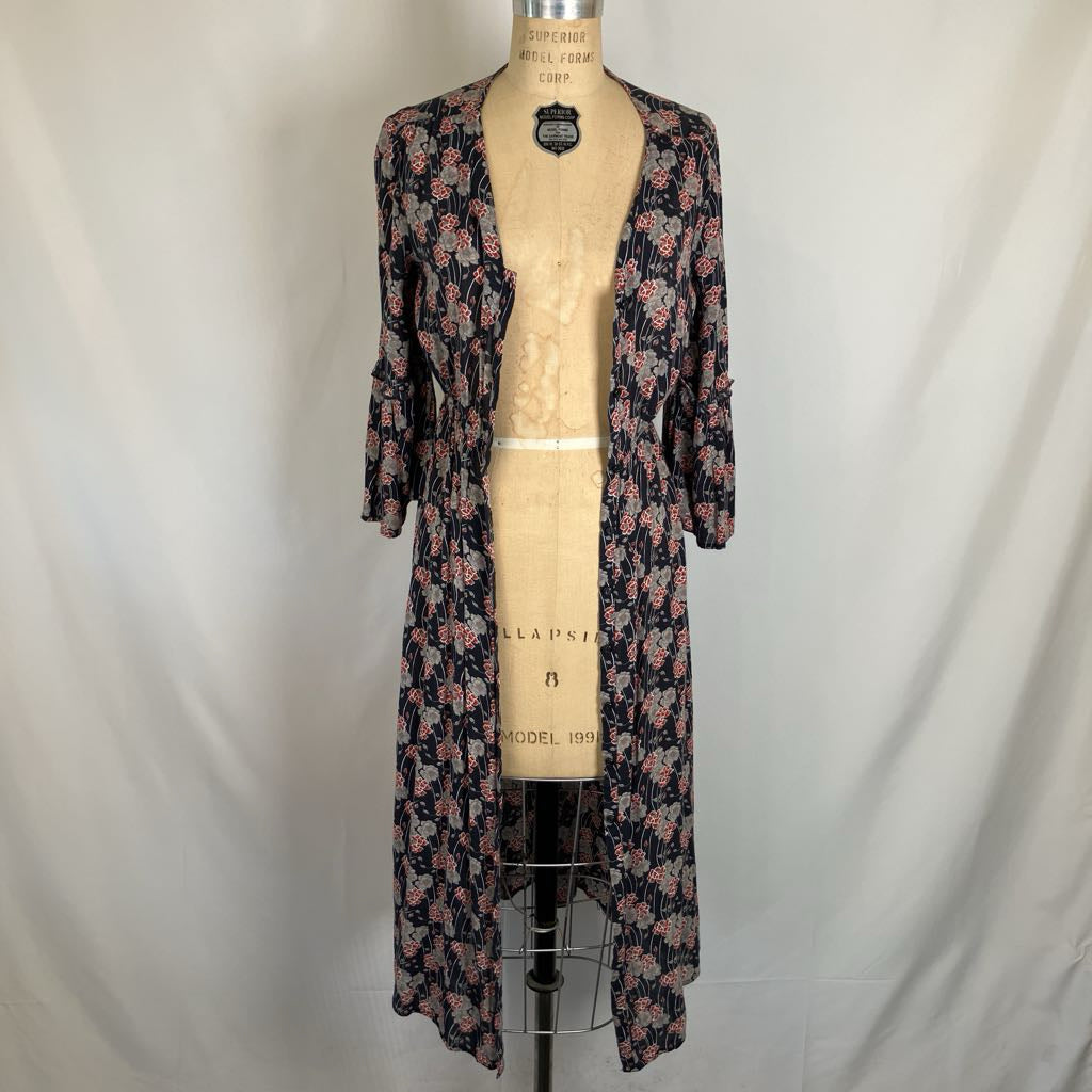 A long-sleeve floral open-front cardigan or robe displayed on a vintage dress form mannequin against a white fabric backdrop.