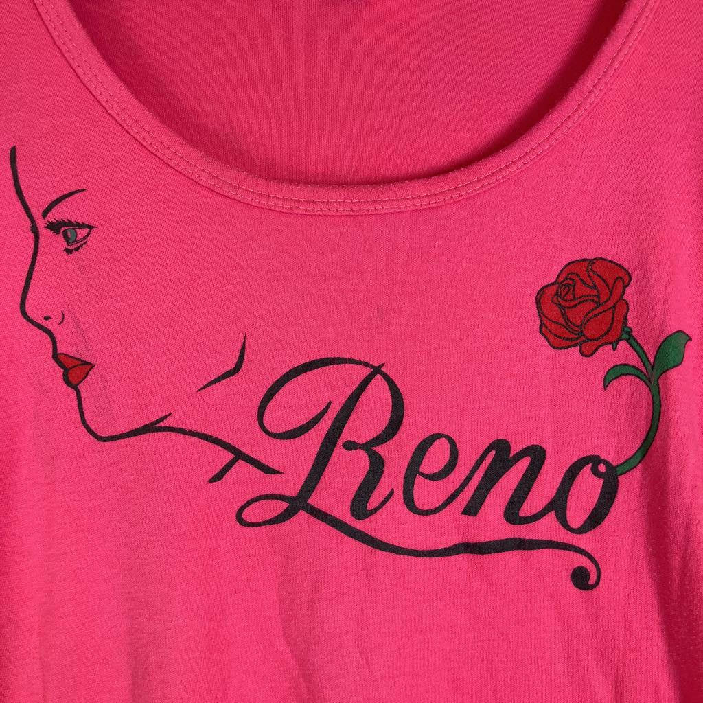 A close-up of a bright pink t-shirt featuring a graphic print of a woman's profile, a red rose, and the name 'Reno' in black cursive script.