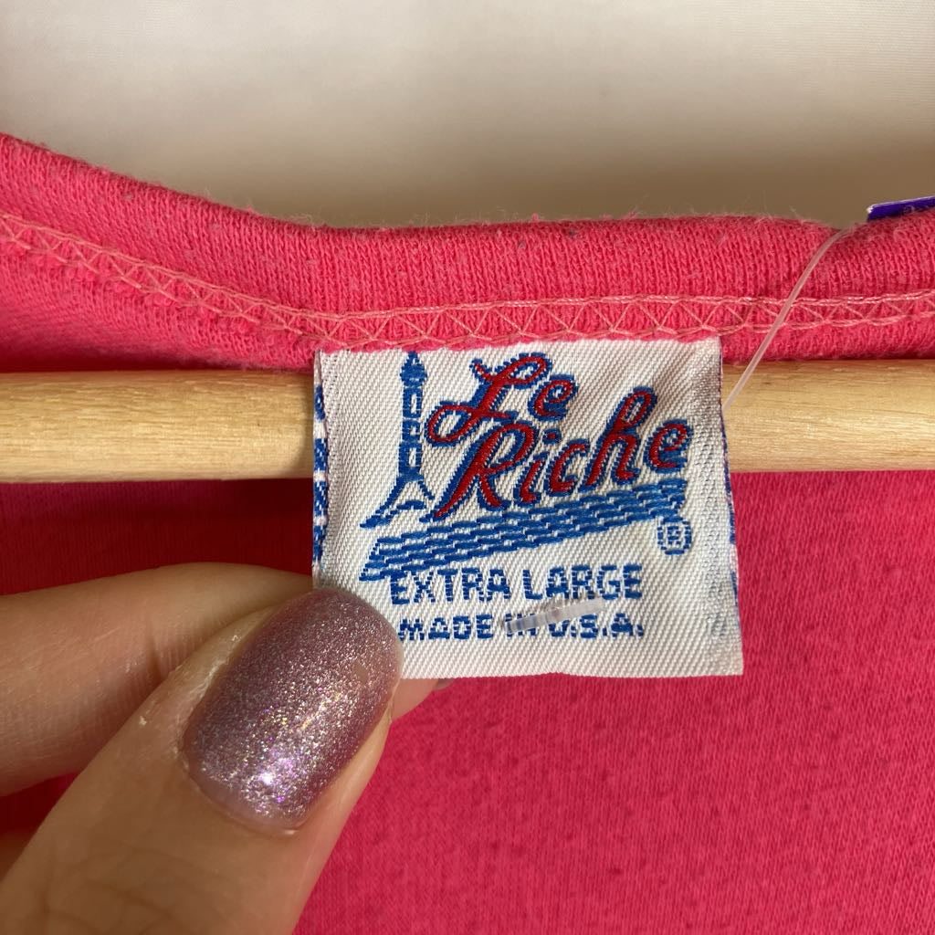 A close-up of a vintage pink garment's inner neck label reading 'Le Riche' and 'EXTRA LARGE MADE IN U.S.